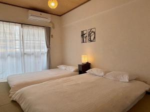 two beds in a room with a window at Neighbor's Hotel 広島駅北口 in Hiroshima