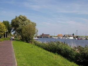 Un camino herboso al lado de un río con barcos. en Ferienhaus Deichstraße 10d, en Carolinensiel