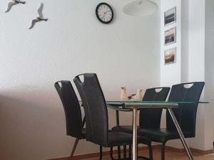 Una mesa de comedor con sillas y un reloj en la pared. en Ferienhaus Deichstraße 10d, en Carolinensiel 13 fotos más