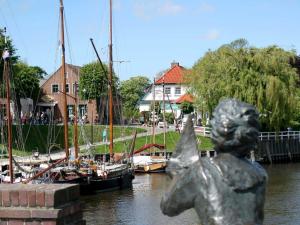 a statue of a girl next to a river with boats at Ferienhaus Schulte in Carolinensiel