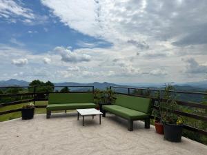 two green benches sitting on a balcony with a view at Karadzhovata Kashta in Zlatograd