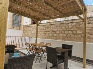 un patio con mesa, sillas y pared de piedra. en B&B Mormina, en Scicli