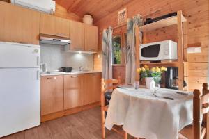a kitchen with a table and a white refrigerator at Chalets 1 MESANGE BLEUE Roquebrune Sur Argens in Roquebrune-sur-Argens