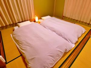 two beds in a room with white sheets at Guest House Korasshai Nakajo in Tokamachi