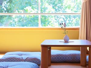 a table with a vase on it in front of a window at Guest House Korasshai Nakajo in Tokamachi