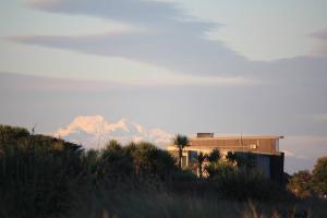 a mountain in the distance with a building and palm trees at Hokitika Beach Break in Hokitika