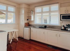 a kitchen with white cabinets and a wooden floor at Hokitika Beach Break in Hokitika