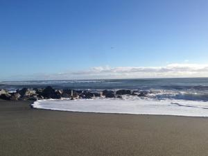 a beach with the ocean and rocks in the sand at Hokitika Beach Break in Hokitika