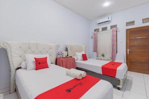 Habitación con 2 camas y sábanas rojas y blancas. en RedDoorz Syariah near Alun Alun Sumedang en Sumedang