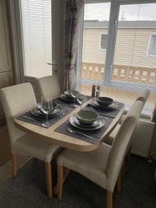 a wooden table with chairs and plates and wine glasses at No. 40 Golf View in Jedburgh