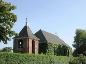 a brick church with a steeple on top of a hedge at Haus Margret in Carolinensiel