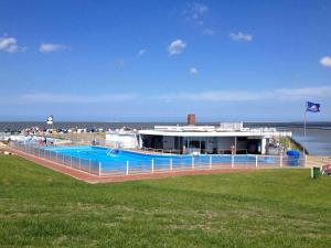 a building with a large swimming pool next to the water at Haus Margret in Carolinensiel