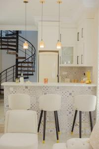 a kitchen with three white chairs and a counter at Maison SOUAD in Mahdia