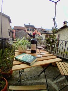 un tavolo in legno con una bottiglia di vino e un bicchiere di Casa Longhi a Orta San Giulio