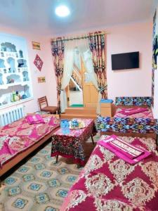 a room with two beds and two tables in it at Fayz Hotel in Bukhara