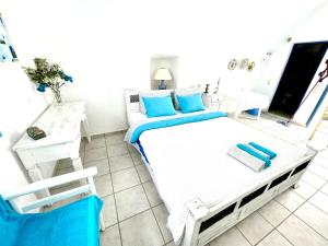 a bedroom with a bed with blue pillows on it at Oia Sunset House Pothitou in Oia