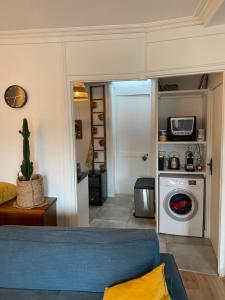 a living room with a blue couch and a washing machine at Disneyland & Paris - JO 2024 - 4 personnes in Crecy la Chapelle