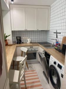 a kitchen with white cabinets and a washer and dryer at Best apartments on Lyatoshinsky street in Zhytomyr