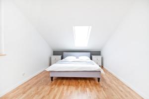 a white bedroom with a bed and a wooden floor at Apartamenty LAGOM in Siedlce