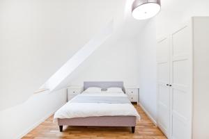 a white bedroom with two beds and a staircase at Apartamenty LAGOM in Siedlce