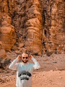 a man is standing in front of a canyon at RUM YANAL CAMP in Wadi Rum