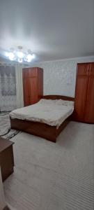een slaapkamer met een bed en een houten kast bij Emir guest house in Batken