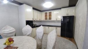 een keuken met een tafel en stoelen en een zwarte koelkast bij Emir guest house in Batken