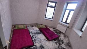 two beds in a room with two windows at Emir guest house in Batken