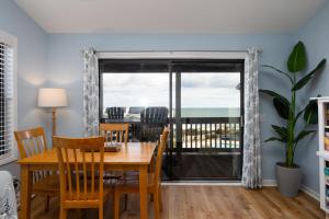 ein Esszimmer mit einem Tisch, Stühlen und einem Fenster in der Unterkunft Sun Catcher Oceanfront Pool Balcony in North Topsail Beach