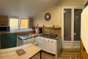 eine Küche mit einem Waschbecken und einer Uhr an der Wand in der Unterkunft Gîte : La Petite Grange in Valojoulx