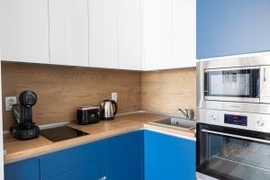 a kitchen with blue cabinets and a microwave at ELINOR Apartments - B25 in St. St. Constantine and Helena