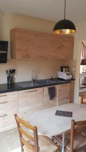 uma cozinha com um lavatório e uma mesa com cadeiras em La Gloriette des Eglantines em Saint-Gervais-la-Forêt
