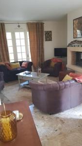 uma sala de estar com um sofá e uma mesa em La Gloriette des Eglantines em Saint-Gervais-la-Forêt