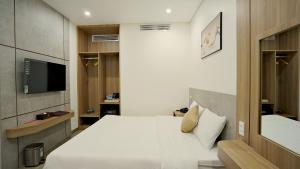 1 dormitorio con 1 cama blanca y TV en Thành Thuý Hotel en Buon Ma Thuot