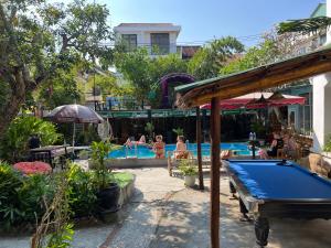 a pool table in front of a swimming pool at Heliport Hostel in Hoi An