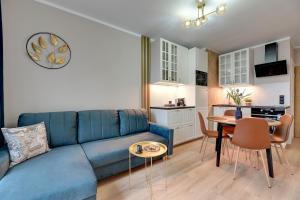 a living room with a blue couch and a table at Downtown Apartments Seaside Baltea Park & Parking in Gdańsk