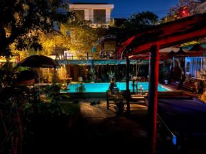 a swimming pool at night with a person sitting by it at Heliport Hostel in Hoi An