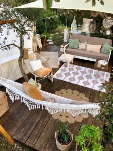 a hammock on a deck with a couch and chairs at Glamping - La Casa del Piano in Chiclana de la Frontera