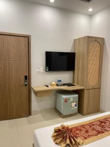 Zimmer mit einem Schreibtisch, einem TV und einer Tür in der Unterkunft Khoa Hotel Phan Thiết in Ấp Bình Hưng