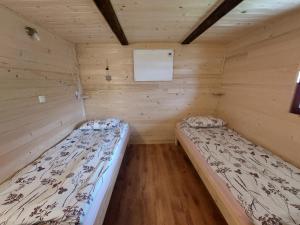1 dormitorio con 2 camas en una habitación de madera en Glamping Laze, en Gorenja Vas
