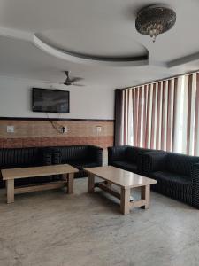 ein Wartezimmer mit Sofas, Tischen und einem TV in der Unterkunft Hotel Parbhat Palace in Katra