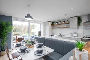 a dining room with a table and a kitchen at NR RHOSNEIGR-3 BED-STYLISH-RE-FURBISHED HOLIDAY HOME in Rhosneigr