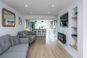 a living room with a gray couch and a kitchen at NR RHOSNEIGR-3 BED-STYLISH-RE-FURBISHED HOLIDAY HOME in Rhosneigr