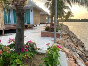 a house on the shore of a body of water with flowers at Nov Koh Kong Resort in Phumĭ Srê Thmei