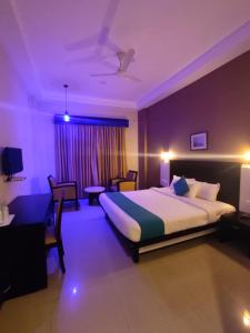 um quarto de hotel com uma cama, uma mesa e cadeiras em Hotel Excalibur em Kottayam