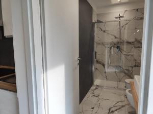 baño con aseo y ducha con paredes de mármol en A Casa Mia 2.0, en Saronno