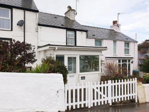 a white fence in front of a white house at NR RHOSNEIGR-3 BED-STYLISH-RE-FURBISHED HOLIDAY HOME in Rhosneigr