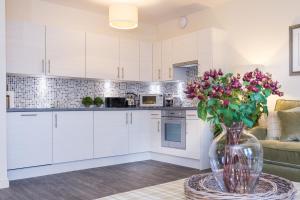 una cocina con armarios blancos y un jarrón de flores sobre una mesa en Town and Country Charleston Apartments, en Aberdeen