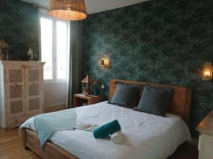 een slaapkamer met een groot bed met groen behang bij La maison O kiwis - Chambres d'hôtes in Saint-Denis-lès-Martel