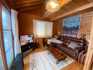 oasis biei في بيي: غرفة معيشة مع أريكة جلدية وتلفزيون بشاشة مسطحة